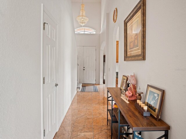 18744 Sabal St, Orlando, FL 32833 - foyer entrance with arched walkways, a high ceiling, a chandelier, light marble finish flooring, and baseboards