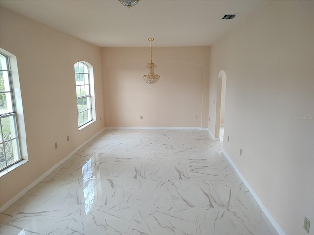 unfurnished room featuring baseboards, visible vents, arched walkways, and marble finish floor