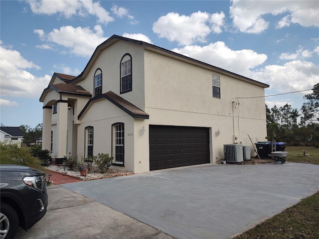 view of front of property with central AC unit, an attached garage, concrete driveway, and stucco siding