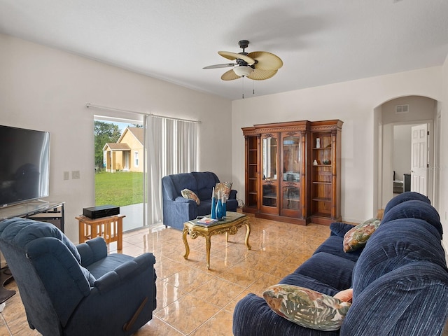 living area with visible vents, arched walkways, and ceiling fan