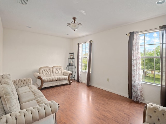 living area with visible vents, baseboards, and wood finished floors