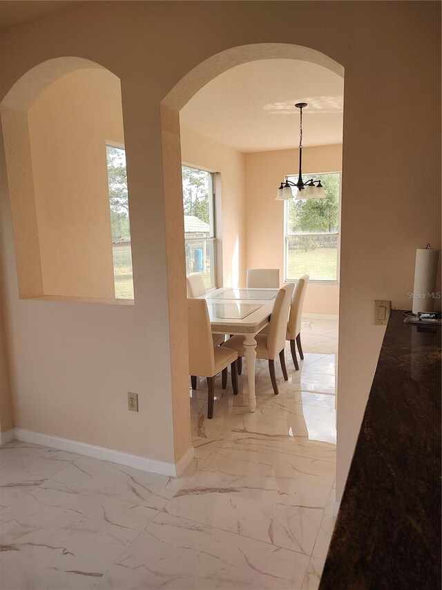18744 Sabal St, Orlando, FL 32833 - dining area with arched walkways, light marble finish floors, baseboards, and a chandelier