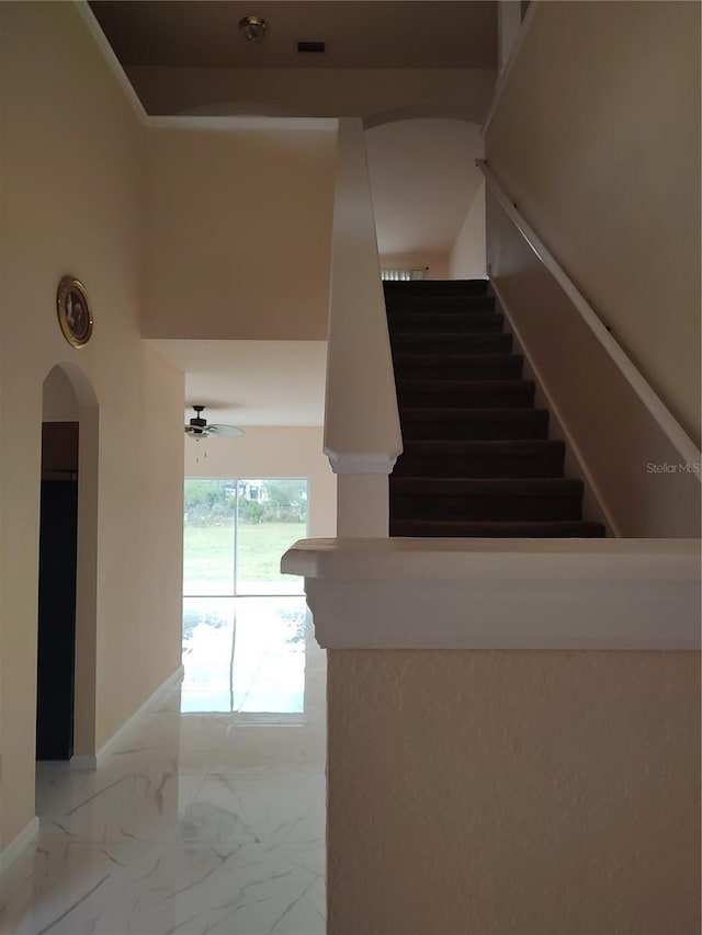 18744 Sabal St, Orlando, FL 32833 - stairway featuring marble look tiles, arched walkways, ceiling fan, and baseboards