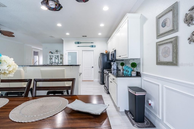 kitchen featuring recessed lighting, tasteful backsplash, appliances with stainless steel finishes, dark countertops, and white cabinetry