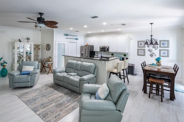 living room with visible vents, ornamental molding, and ceiling fan with notable chandelier