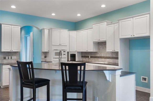 kitchen featuring a center island with sink and white cabinets