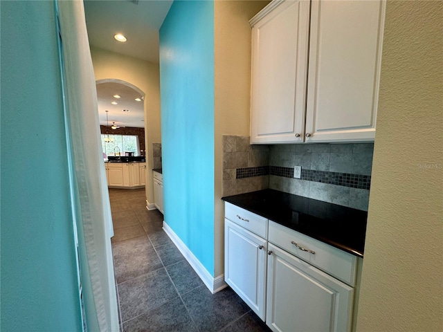 kitchen featuring white cabinets, decorative backsplash, and dark tile patterned floors