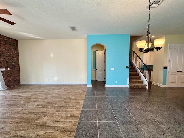 interior space with ceiling fan with notable chandelier and a textured ceiling