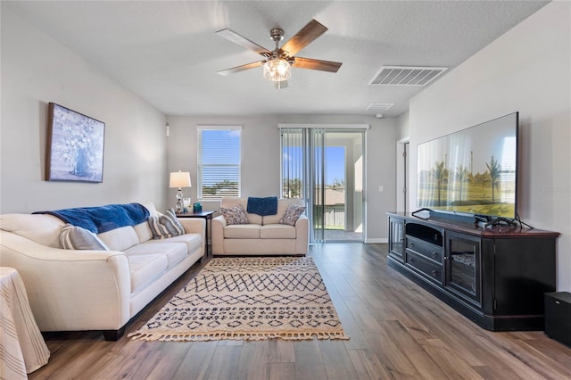 living room featuring ceiling fan, a textured ceiling, and hardwood / wood-style floors