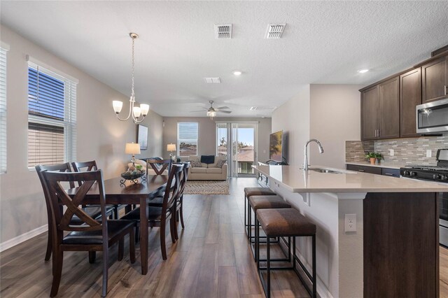 dining area featuring a textured ceiling, ceiling fan with notable chandelier, dark hardwood / wood-style floors, and sink