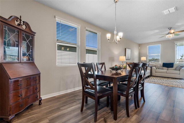 dining room with ceiling fan with notable chandelier, dark hardwood / wood-style flooring, and a textured ceiling