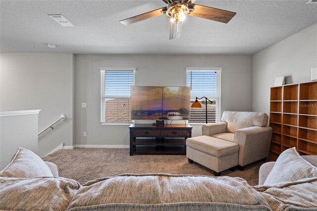 living room with a textured ceiling, ceiling fan, and carpet flooring