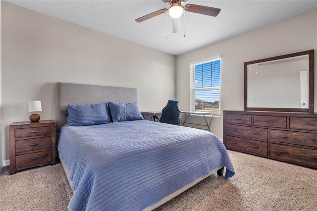 bedroom featuring ceiling fan, light colored carpet, and a textured ceiling