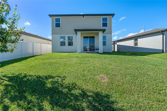 rear view of property featuring a patio and a yard