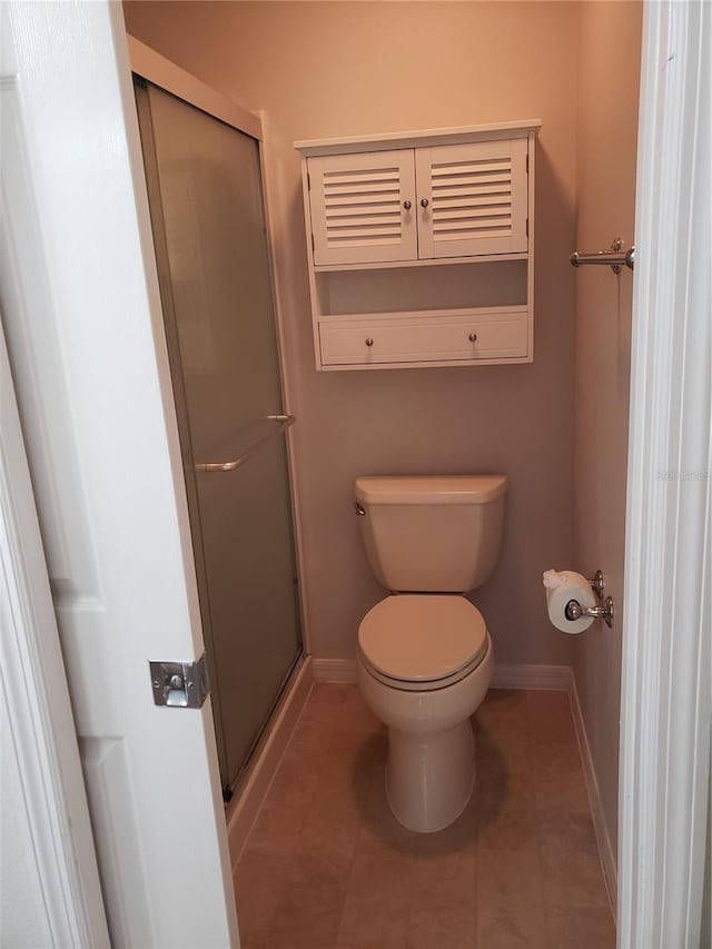 bathroom with a shower with door, toilet, and tile patterned flooring