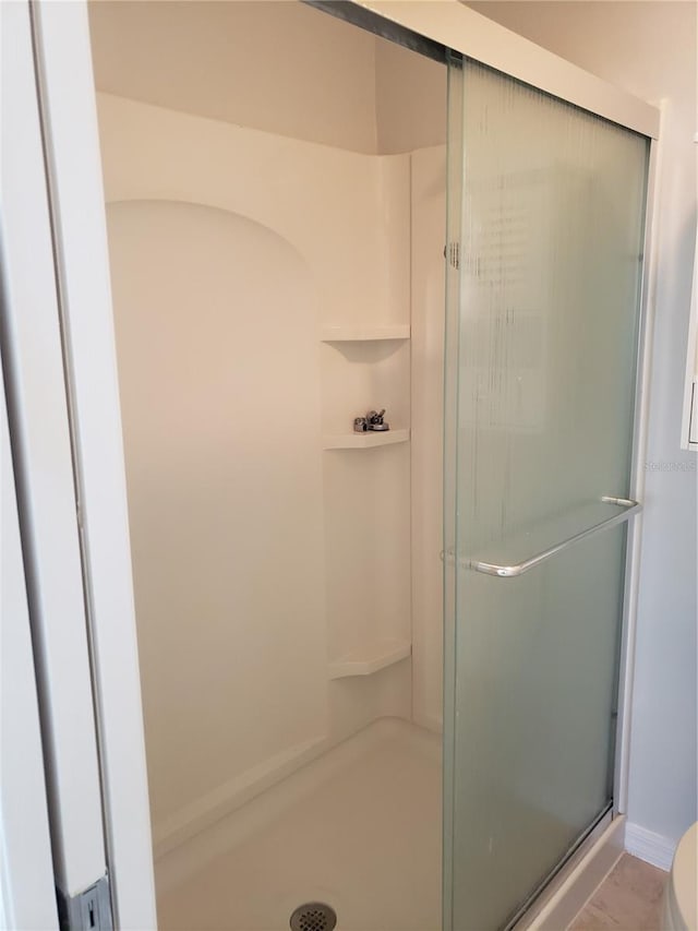 bathroom with a shower with door and toilet