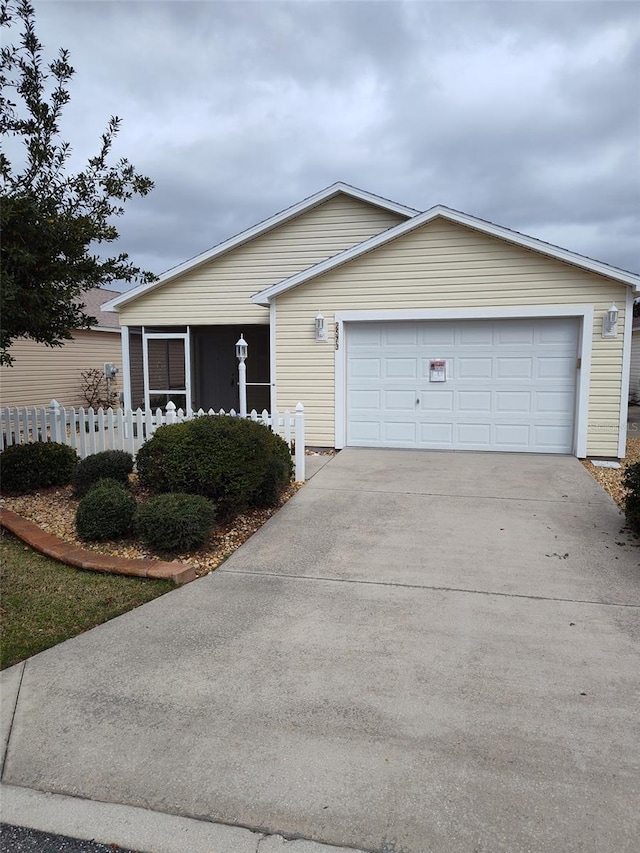 ranch-style house featuring concrete driveway, fence, and an attached garage