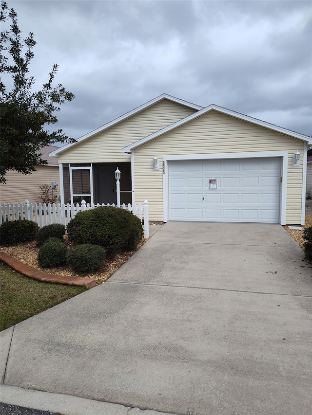 ranch-style home with driveway, an attached garage, and fence