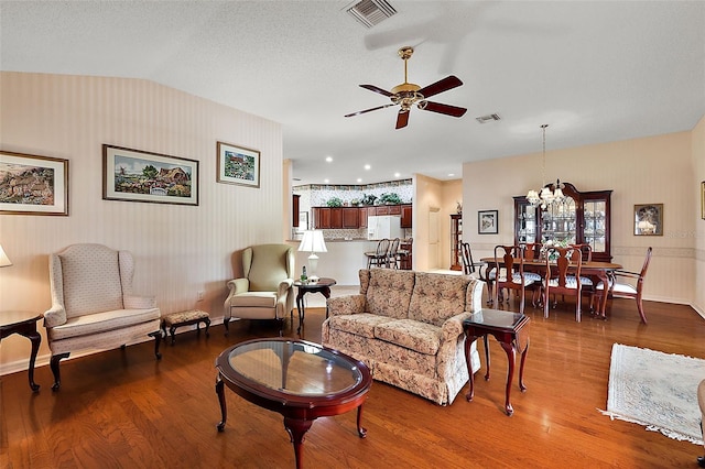 living room featuring hardwood / wood-style floors, a textured ceiling, ceiling fan with notable chandelier, and vaulted ceiling