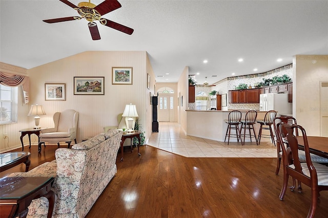 living room featuring vaulted ceiling, light hardwood / wood-style flooring, and ceiling fan