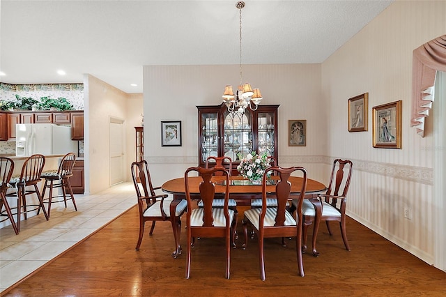 dining area with a textured ceiling, light hardwood / wood-style flooring, and a chandelier