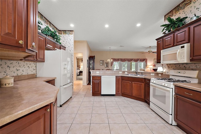 kitchen featuring hanging light fixtures, sink, kitchen peninsula, and white appliances