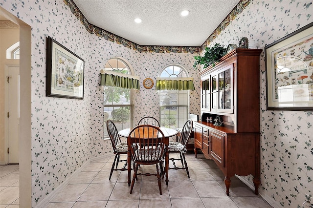 tiled dining room featuring a textured ceiling and a healthy amount of sunlight