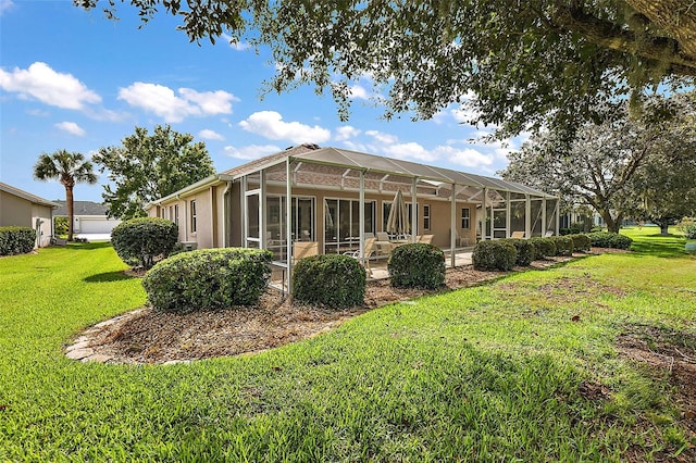 rear view of property featuring a lawn and glass enclosure