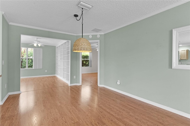 unfurnished room with a textured ceiling, crown molding, light wood-type flooring, and a healthy amount of sunlight