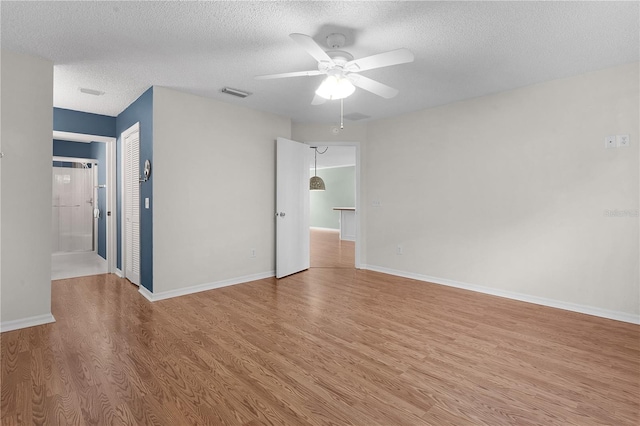 spare room with ceiling fan, a textured ceiling, and light hardwood / wood-style flooring