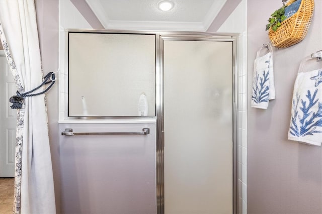 bathroom with a shower with door and ornamental molding