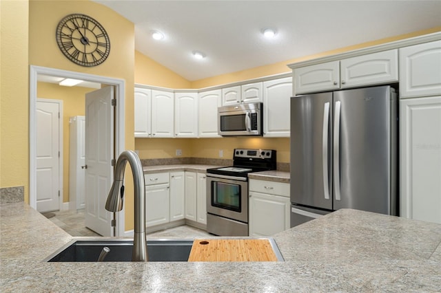 kitchen with white cabinets, stainless steel appliances, sink, and lofted ceiling