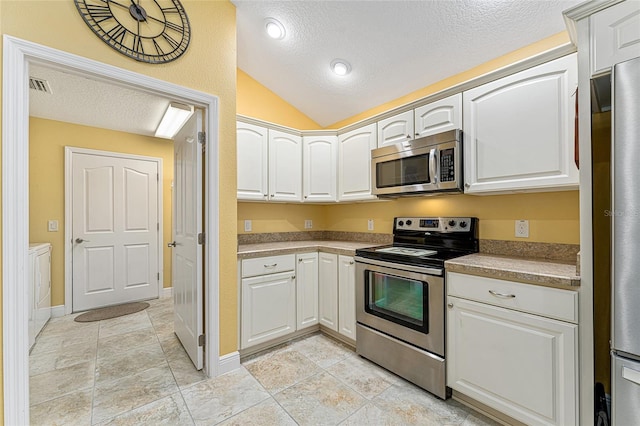 kitchen featuring white cabinets, a textured ceiling, stainless steel appliances, and vaulted ceiling