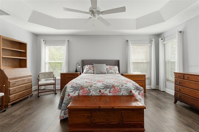 bedroom featuring dark wood-type flooring, a raised ceiling, a textured ceiling, and ceiling fan