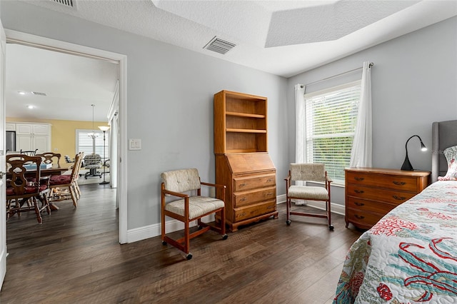 bedroom with a textured ceiling, stainless steel fridge, and dark hardwood / wood-style flooring