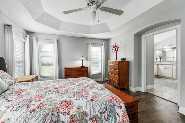 bedroom featuring ceiling fan, sink, dark hardwood / wood-style flooring, ensuite bath, and a textured ceiling