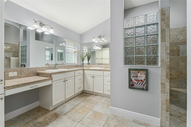 bathroom with vanity, tile patterned flooring, a textured ceiling, a tile shower, and vaulted ceiling