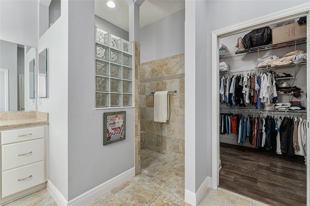 bathroom with wood-type flooring, vanity, and tiled shower