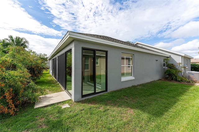 back of property featuring a sunroom and a lawn