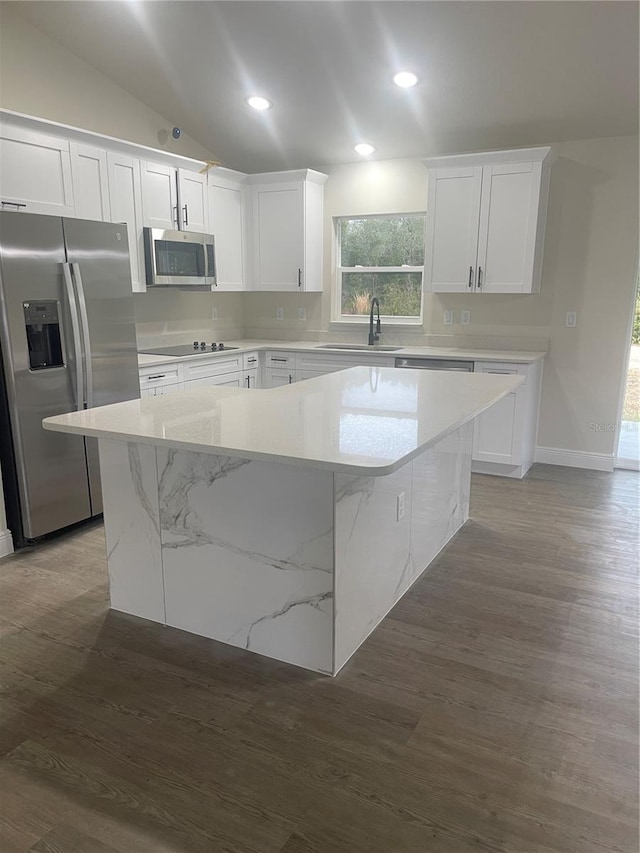 kitchen featuring appliances with stainless steel finishes, sink, a center island, white cabinetry, and lofted ceiling