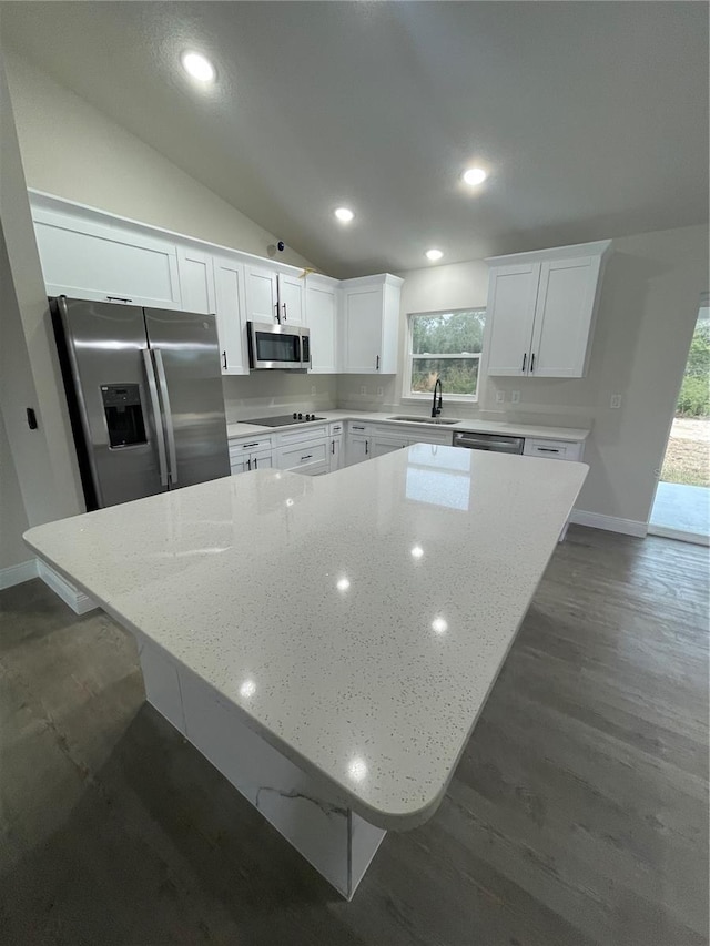 kitchen featuring light stone counters, white cabinets, stainless steel appliances, and lofted ceiling