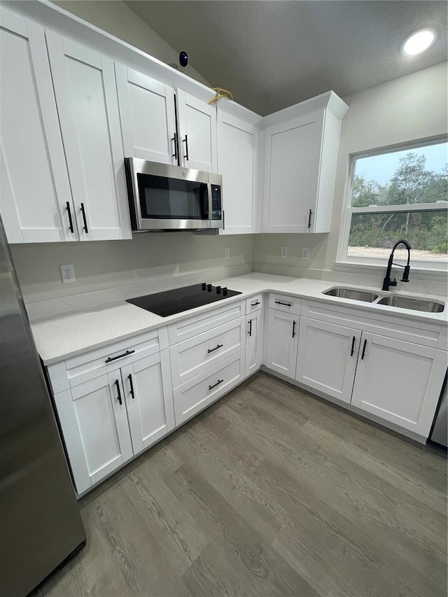 kitchen with white cabinets, stainless steel appliances, light hardwood / wood-style floors, and sink