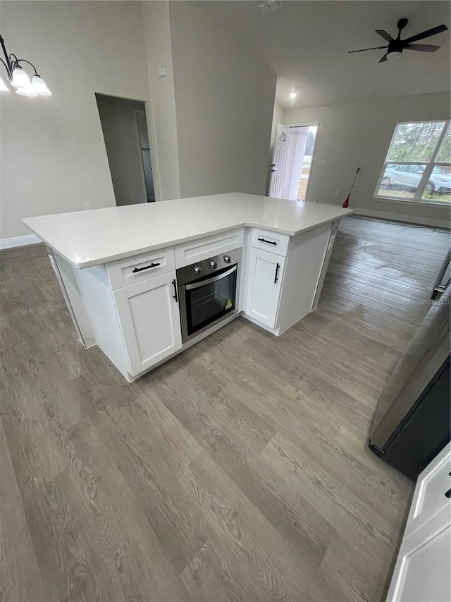 kitchen featuring light wood-type flooring, white cabinetry, a kitchen island, and stainless steel oven