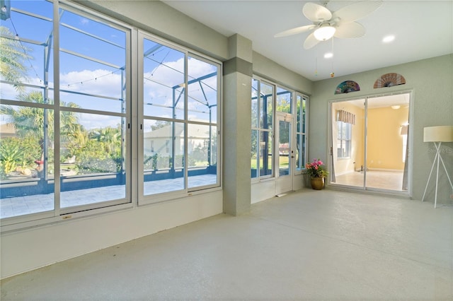 spare room featuring ceiling fan, concrete floors, and plenty of natural light