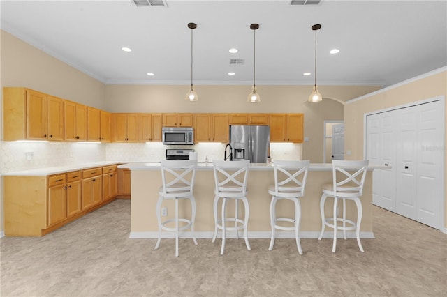 kitchen featuring pendant lighting, ornamental molding, stainless steel appliances, and an island with sink