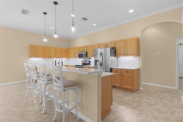 kitchen featuring decorative light fixtures, crown molding, a center island with sink, and stainless steel appliances