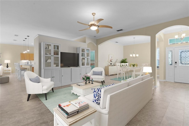 living room featuring ceiling fan with notable chandelier, sink, and ornamental molding