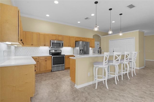 kitchen featuring hanging light fixtures, crown molding, stainless steel appliances, and a center island with sink