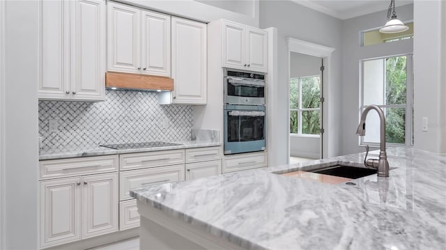 kitchen featuring white cabinets, sink, decorative light fixtures, double oven, and light stone countertops