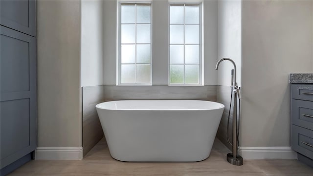 bathroom featuring vanity, tile walls, a washtub, and a wealth of natural light